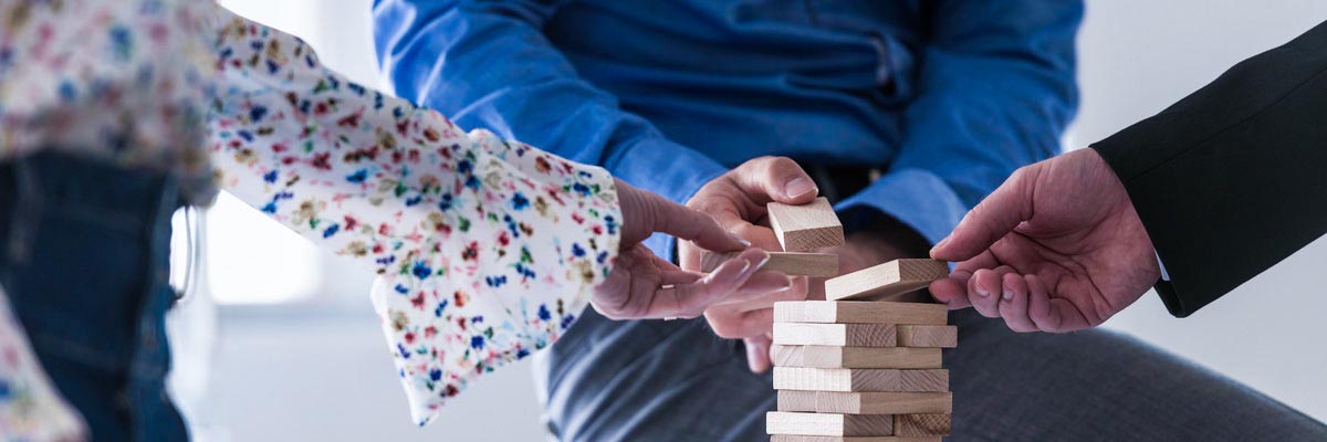 Wide view image of three business people making a tower of woode